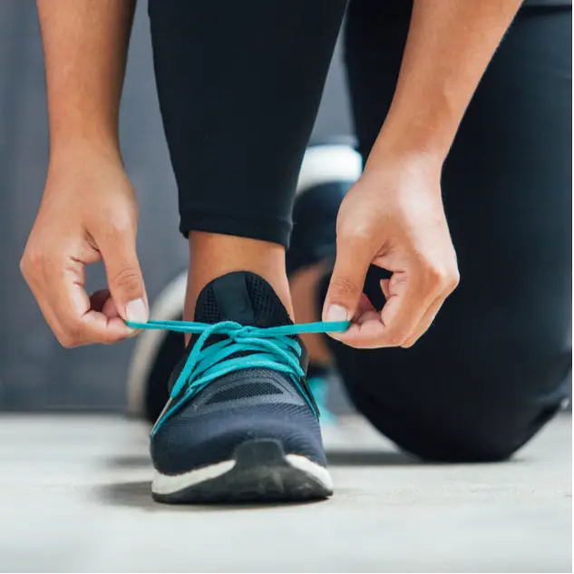 A woman tying her shoes before she starts a home workout